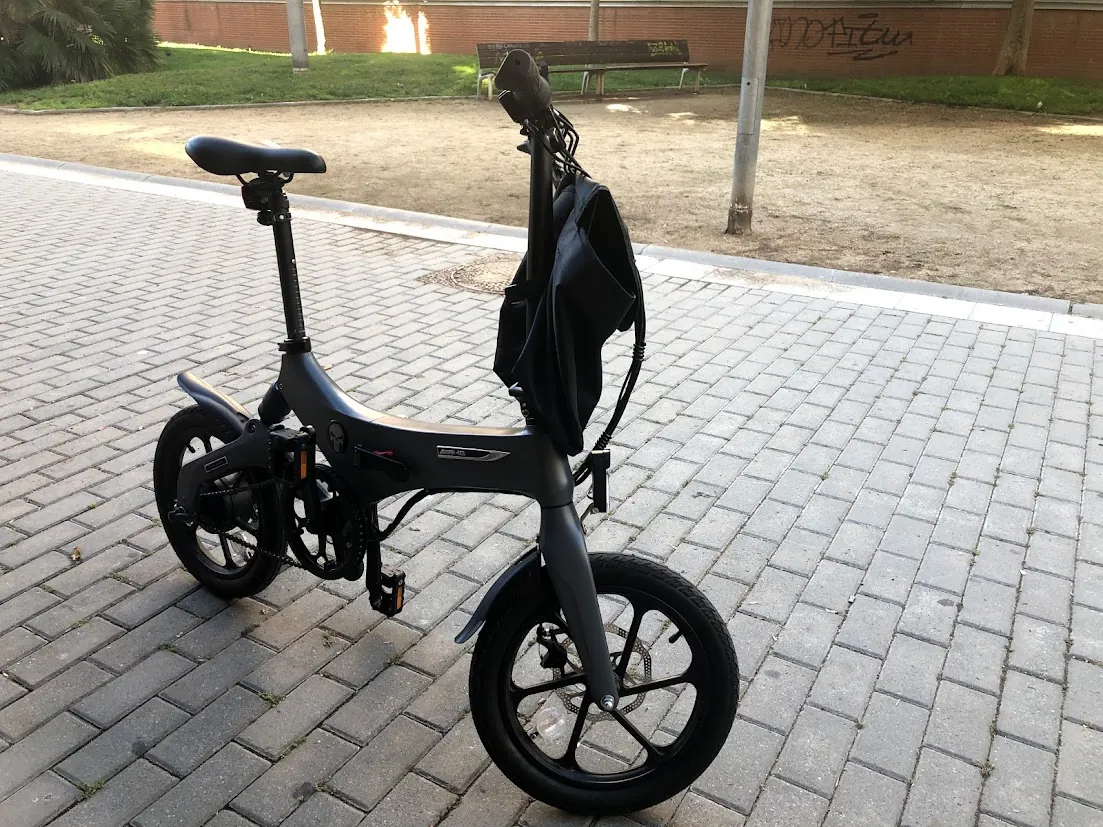 Bicicleta eléctrica plegable negra con mochila en manillar