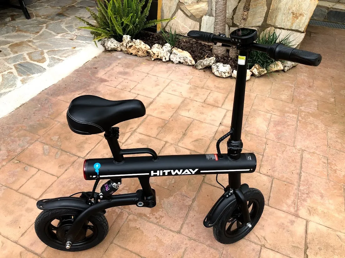 Patinete eléctrico negro con asiento, en suelo de baldosas rojas