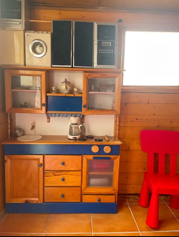 Cocina de juguete con electrodomésticos y un sillón rojo