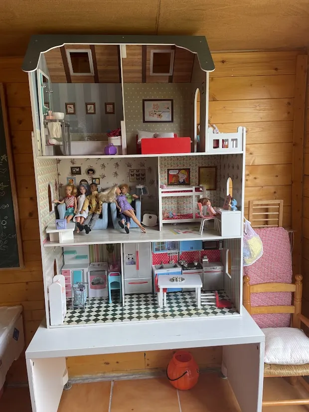Muñeca de porcelana en casa de muñecas de varios pisos con mobiliario