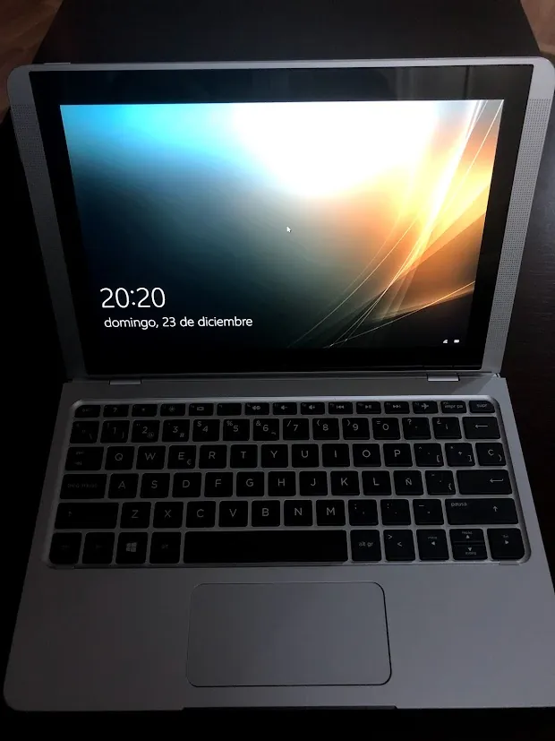 Laptop plateado con pantalla encendida mostrando el día y hora